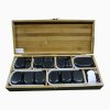 An open bamboo storage box filled with assorted black, white, and colored massage stones organized neatly into felt-lined compartments.