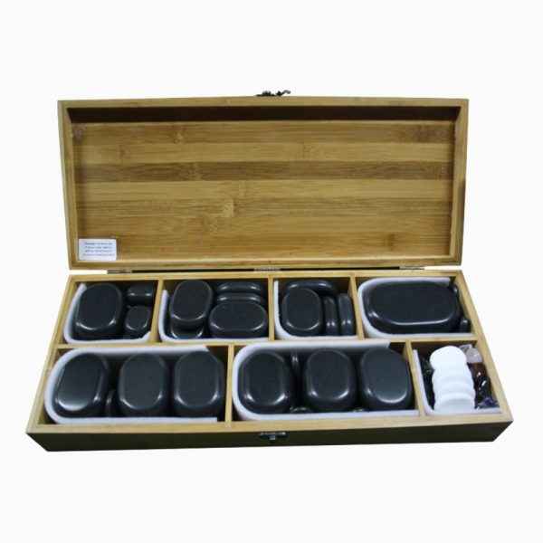 An open bamboo storage box filled with assorted black, white, and colored massage stones organized neatly into felt-lined compartments.