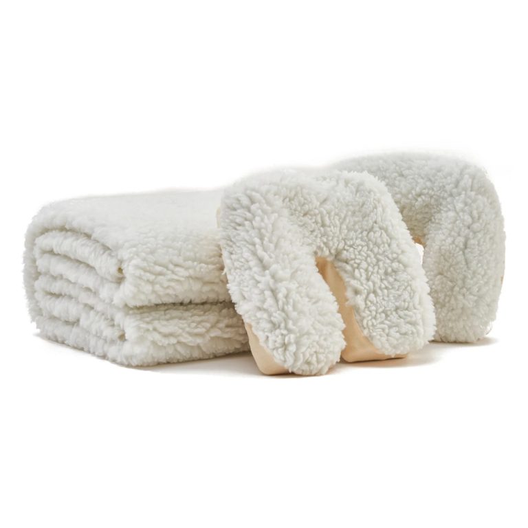 Neatly folded white fleece massage table pad next to a matching white fleece headrest cover, set against a plain background.