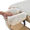 Close-up of a hand resting gently on a thick white sheepskin fleece massage table headrest cover.