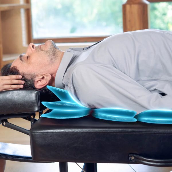 A side view of a person lying on their back on a black massage table, with blue illuminated airbags gently stretching their upper back and shoulder area.