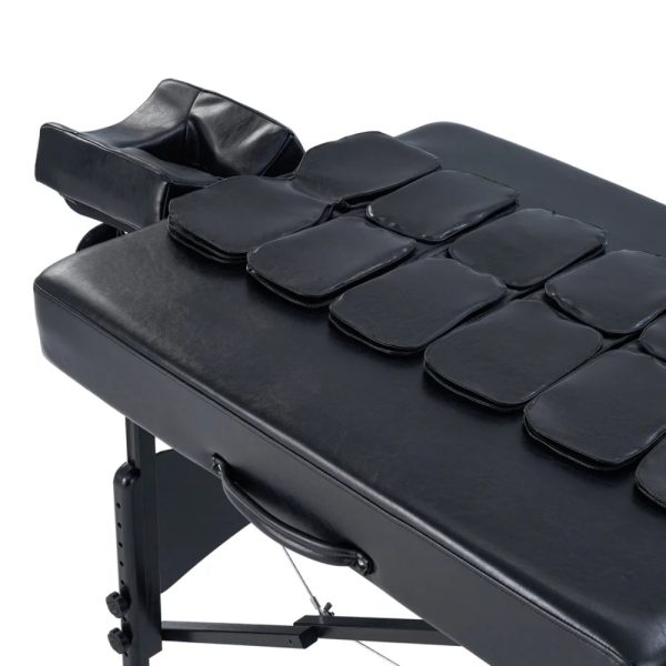 A high-angle close-up of the black upholstery of a professional massage table, featuring a structured grid of integrated airbag modules designed for therapeutic stretching.