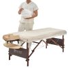 Therapist draping a disposable white fitted cover over a beige massage table.